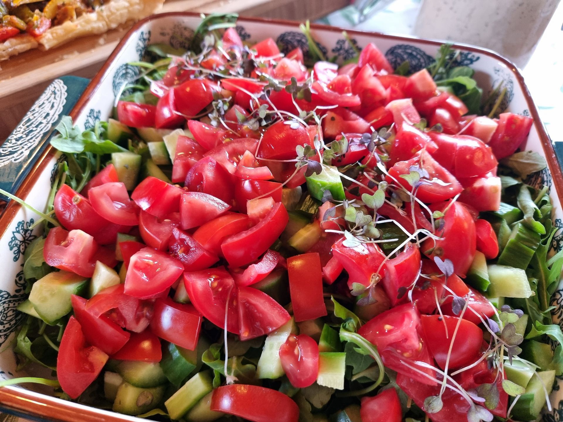 Salade met gehakte rode tomaten, komkommers en bladgroenten in een sierlijke schaal.