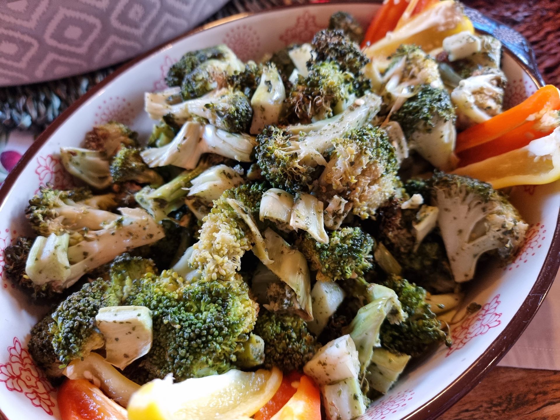Geroosterde broccoli in een kom met een decoratief patroon, gegarneerd met paprika.