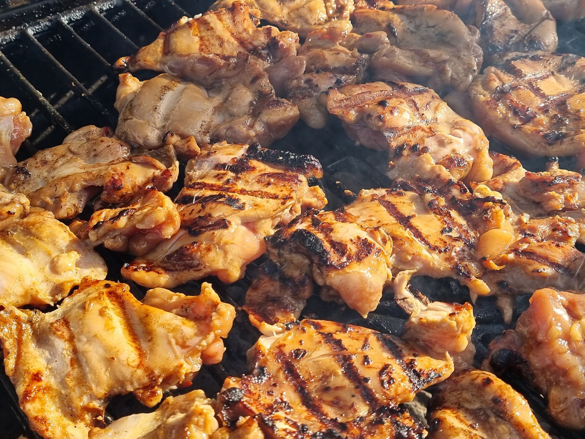 Gegrilde kipstukjes op een hete grill, met grillstrepen.