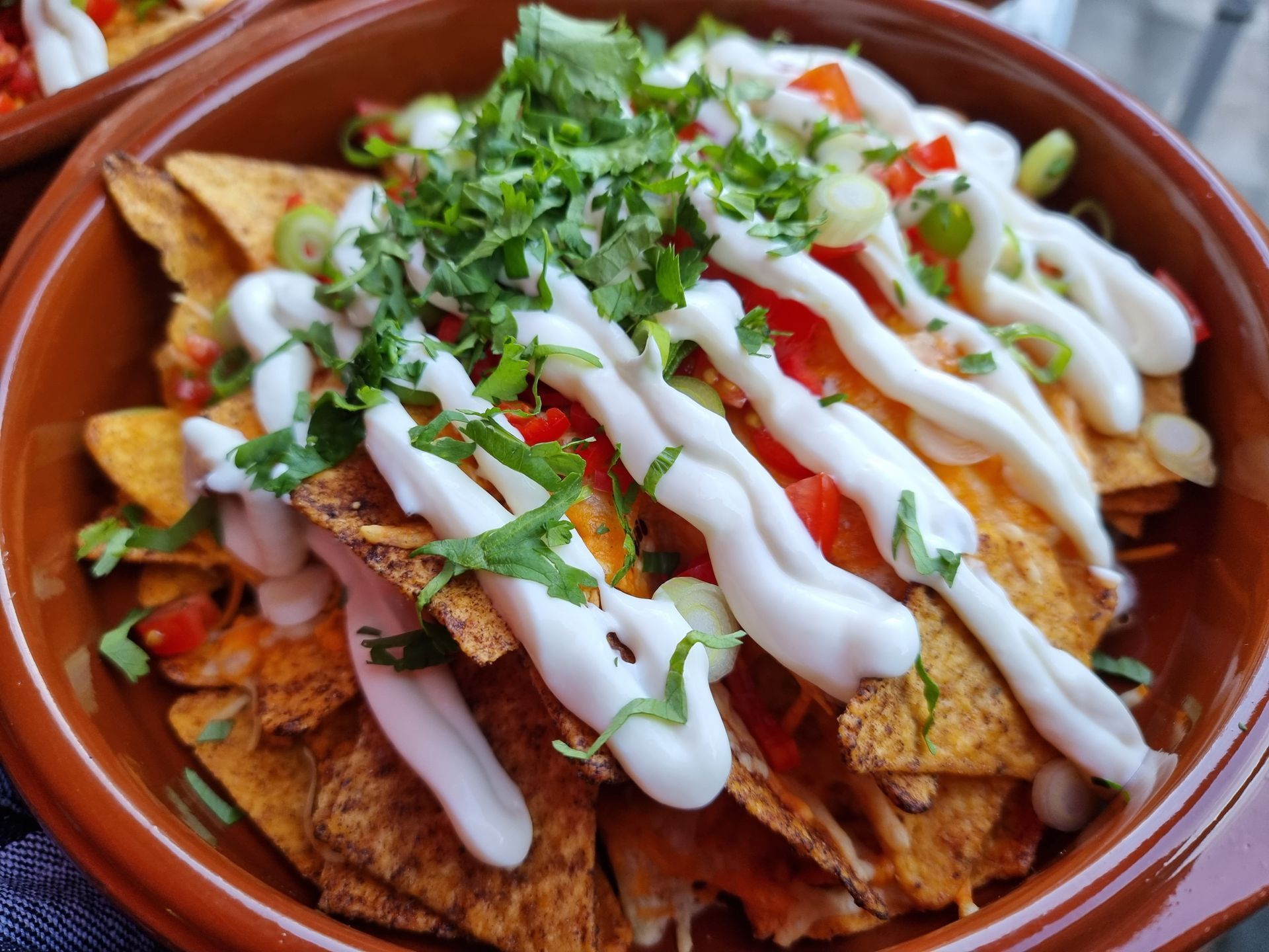 Een kom nacho's: tortillachips met tomaten, witte saus en kruiden.