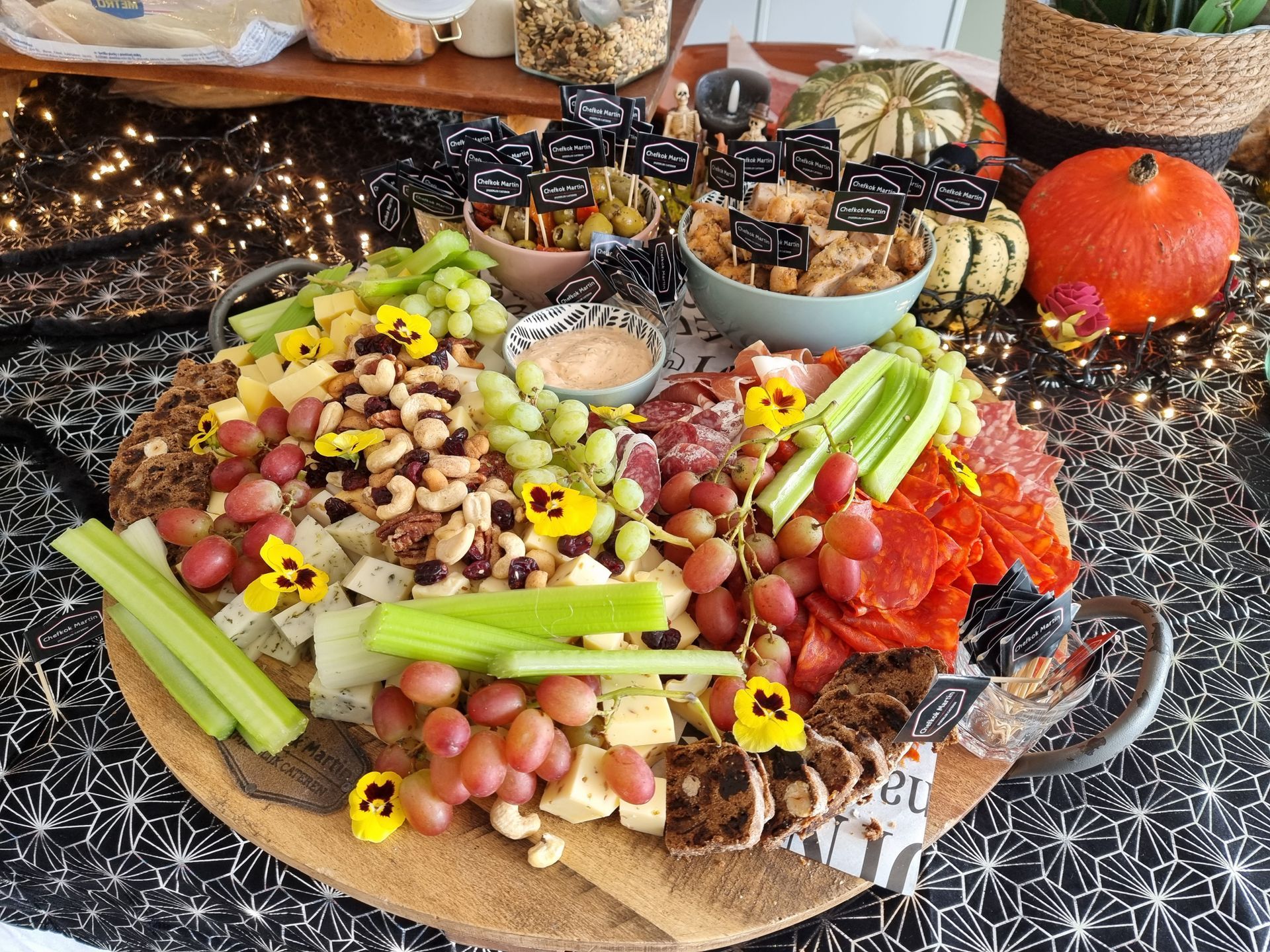Een Halloween-charcuterieplank met kaas, druiven, noten, salami en olijven.