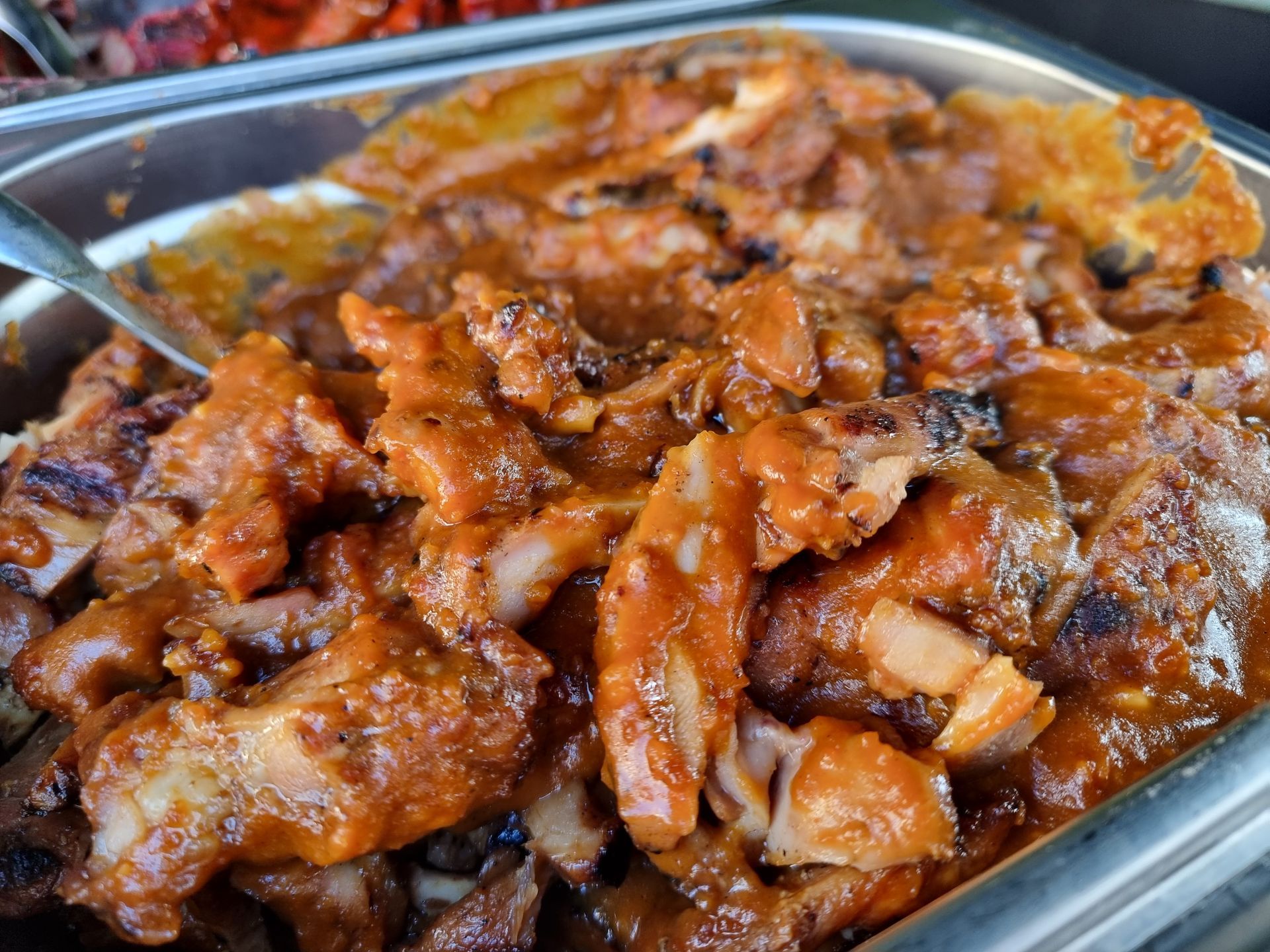 Gegrilde kipstukjes met een roodbruine saus.