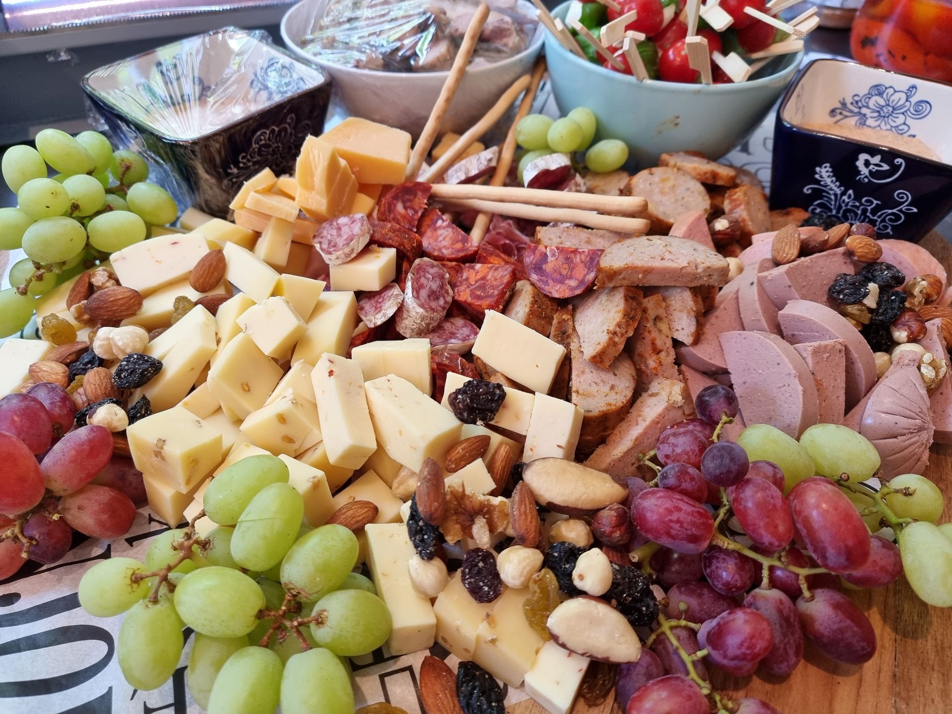 Charcuterieplank met druiven, kaas, vleeswaren, noten, crackers en bijgerechten.
