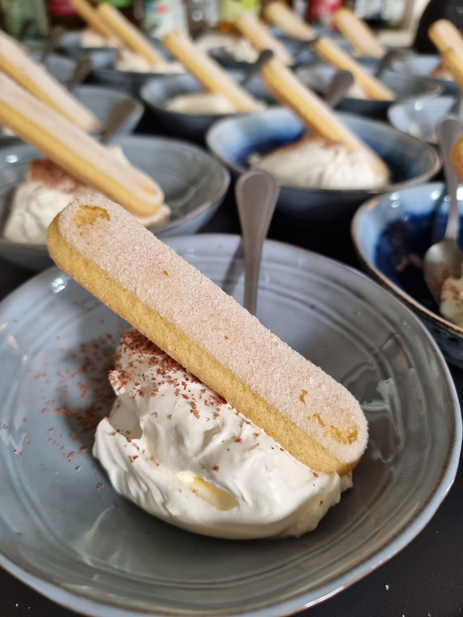 Schalen tiramisucreme, gegarneerd met een langevingers en bestrooid met cacaopoeder, klaar om te serveren.