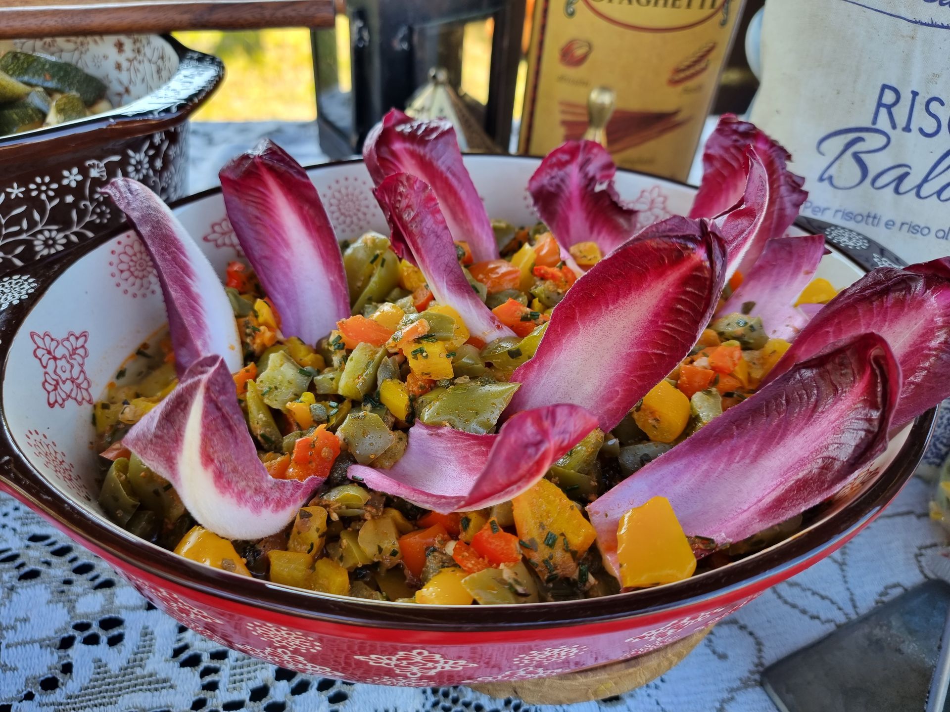 Kleurrijke salade in een rode kom met radicchioblaadjes en in blokjes gesneden groenten.