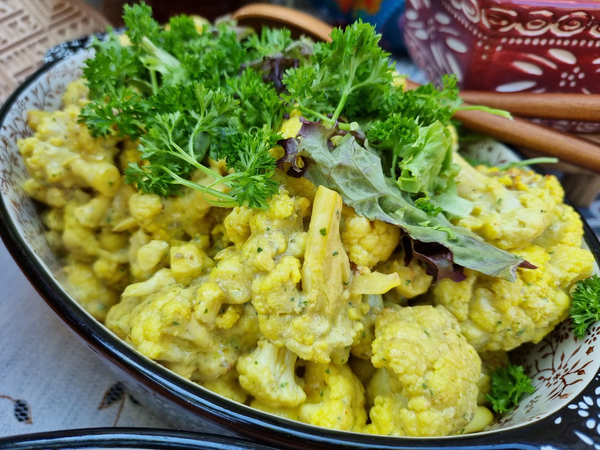Bloemkoolcurry in een decoratieve kom, gegarneerd met peterselie.