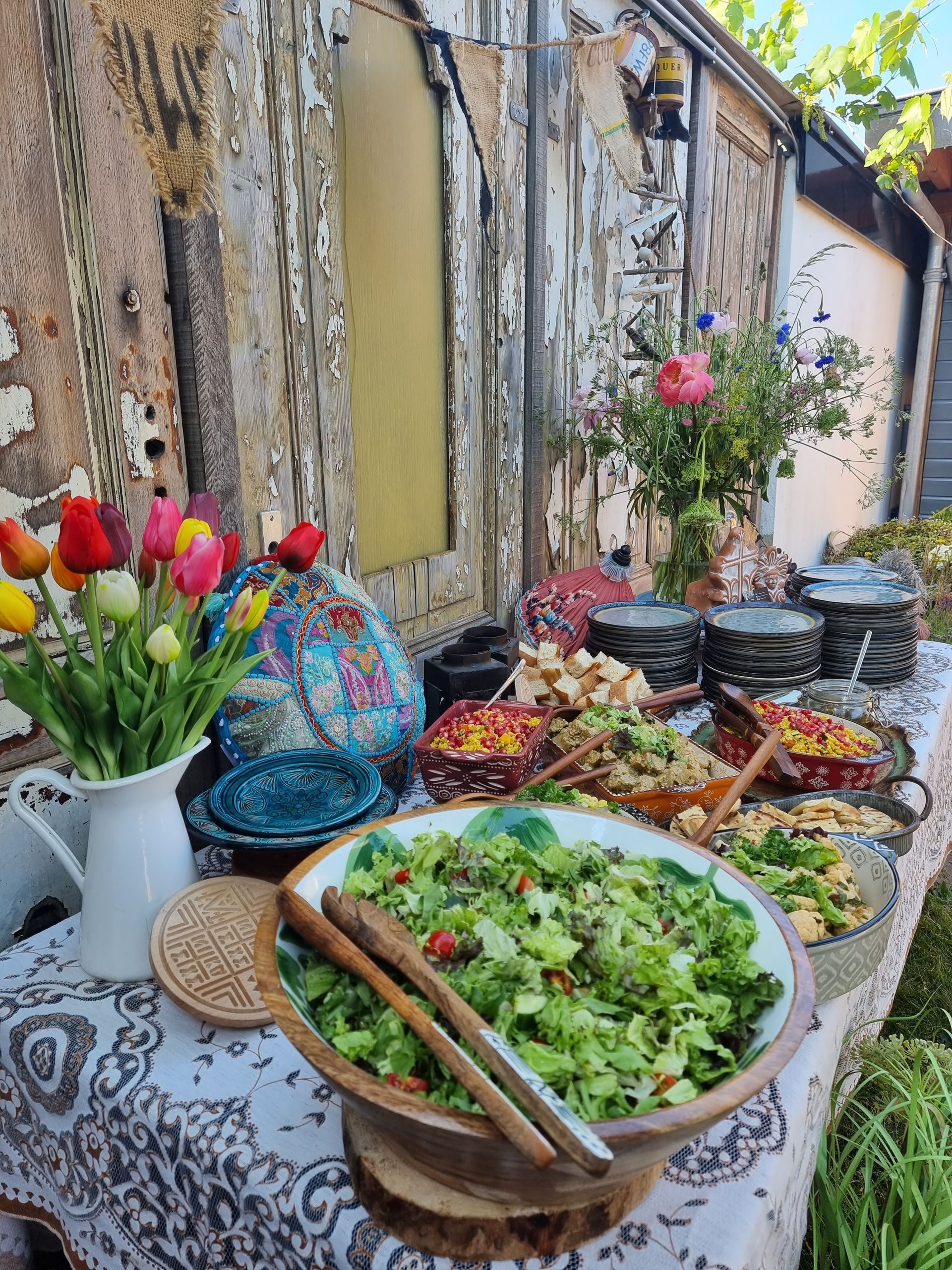 Buffettafel buiten met salades, bloemstukken en diverse gerechten die tentoongesteld staan.