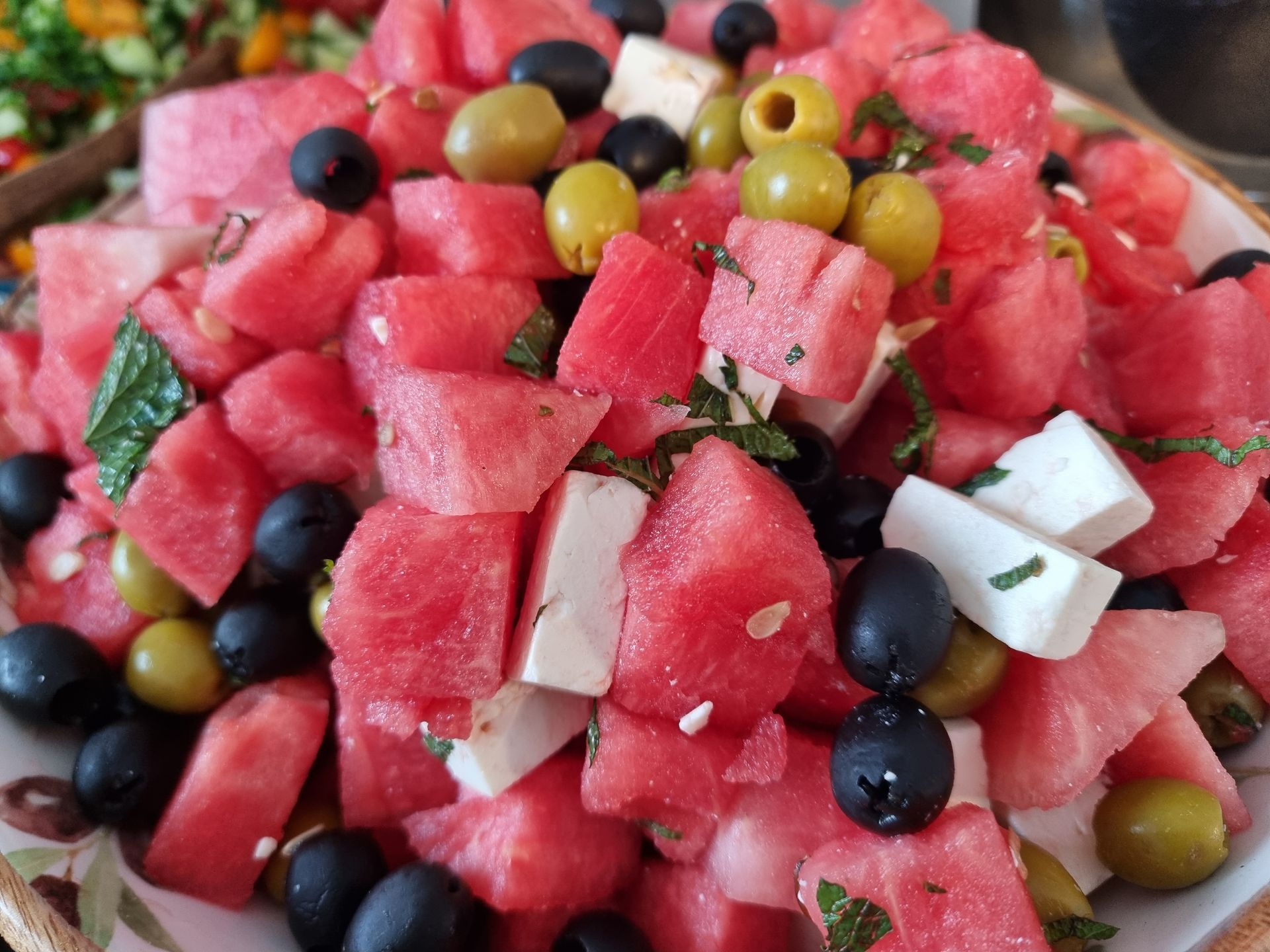 Watermeloensalade met feta, olijven en kruiden in een kom.