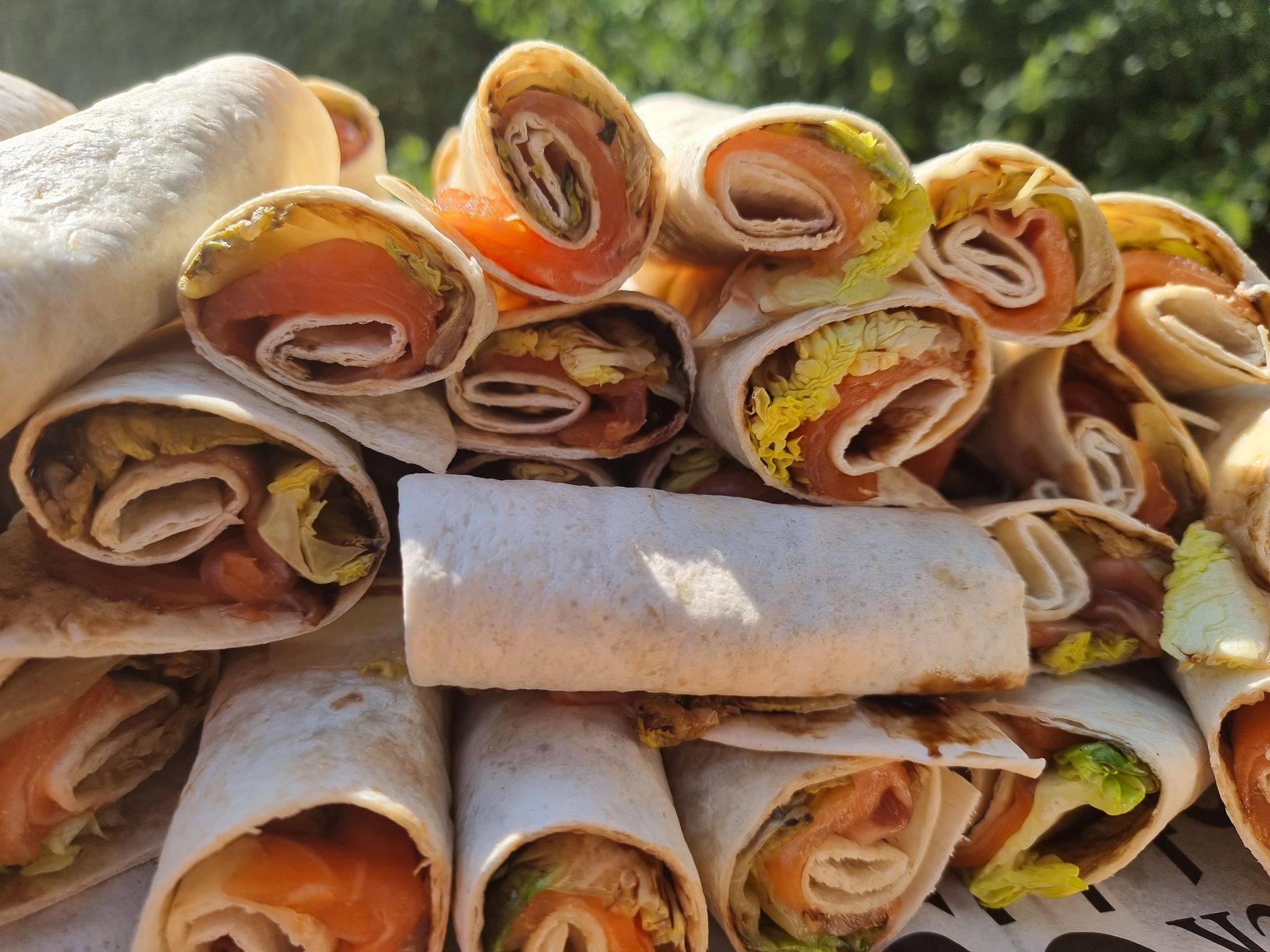 Een stapel opgerolde wraps met zalm en sla.