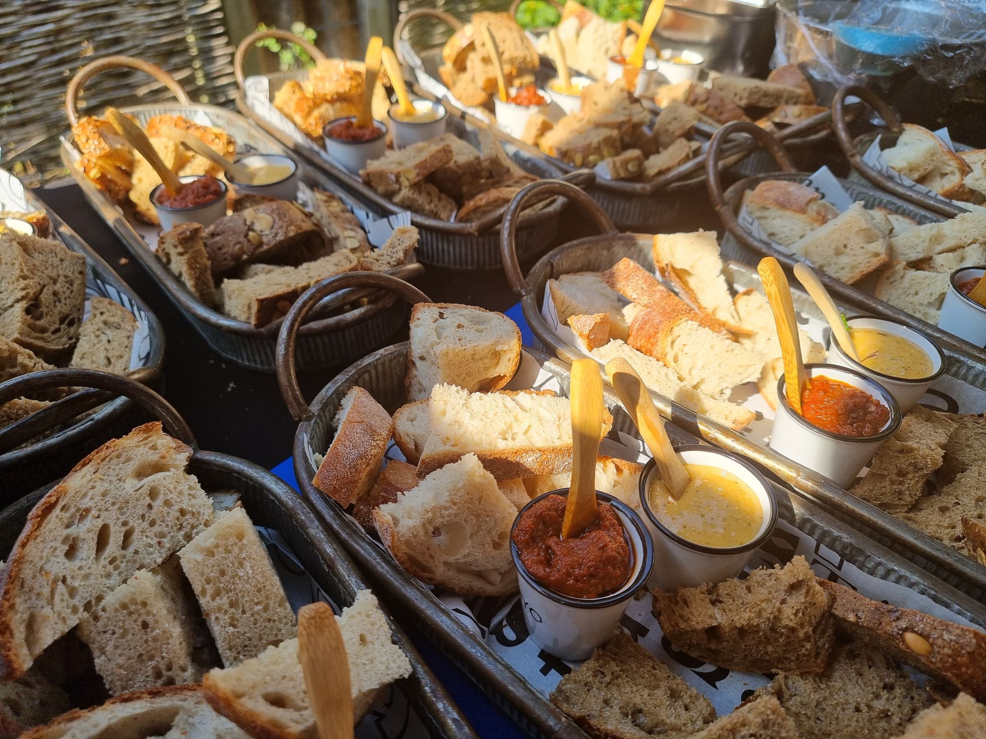 Diverse metalen schuitjes met sneetjes brood met dipsausjes.