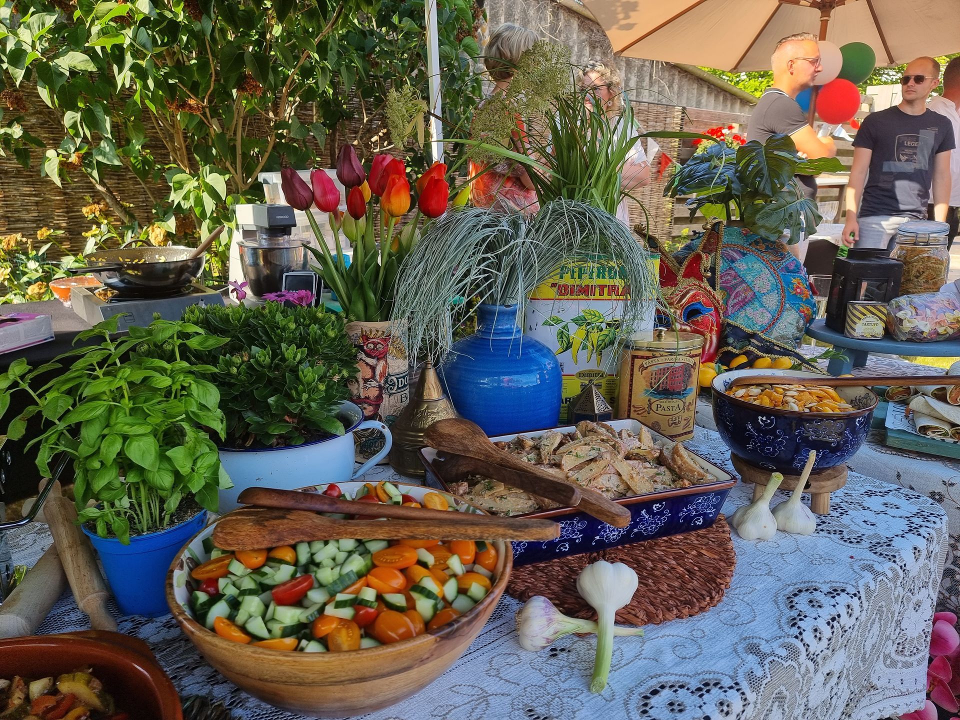 Een buitentafel vol met eten en bloemen.