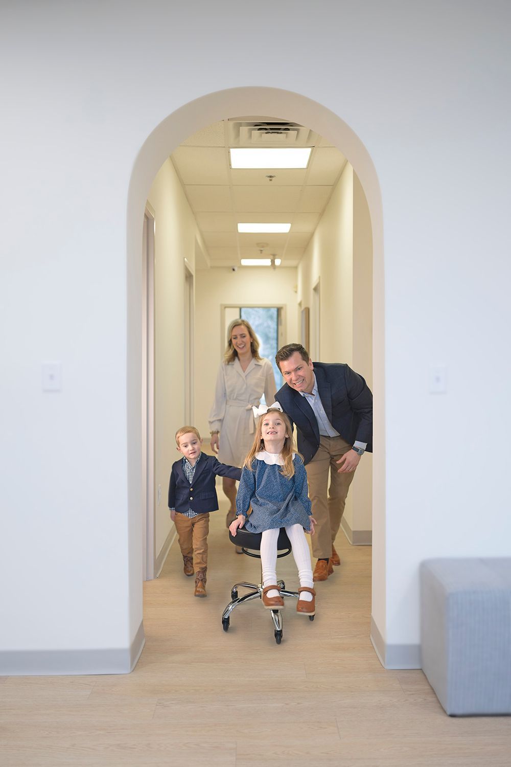 A family is walking down a hallway with a little girl in a wheelchair at Carson Williams MD Facial Plastic Surgery office