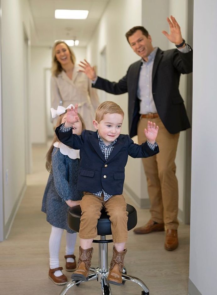 A family is standing in a hallway with a boy sitting on a stool in Leawood KS