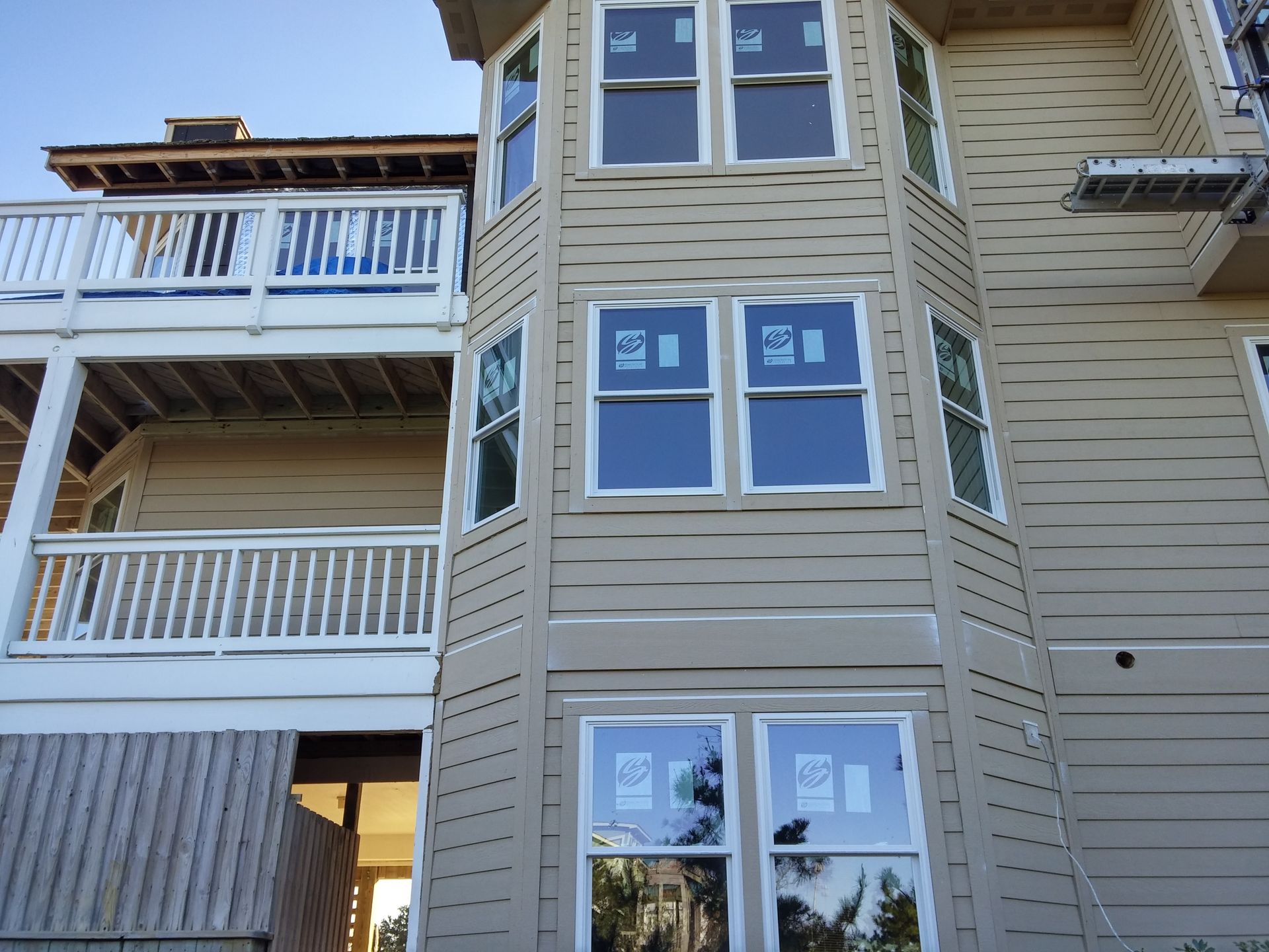 Exterior of a two-story beige house with multiple windows and a white balcony.