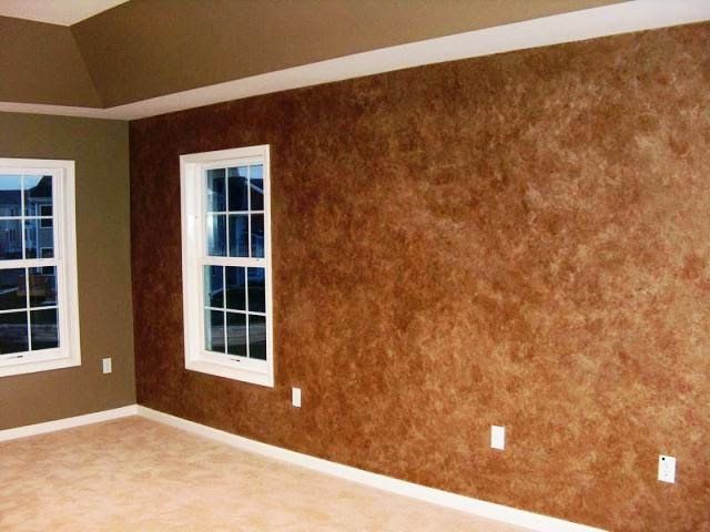 Empty room with textured brown walls, two white-framed windows, and tan carpet.