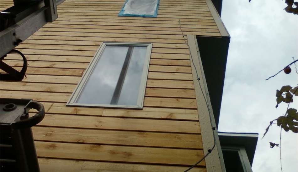 Wooden building with two windows against a cloudy sky.