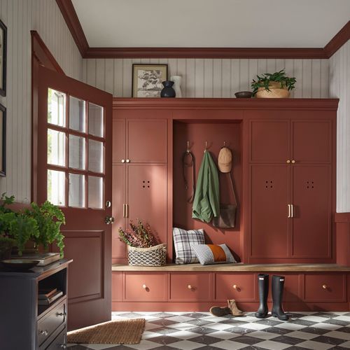 Red mudroom with built-in storage, bench, door, and patterned floor.