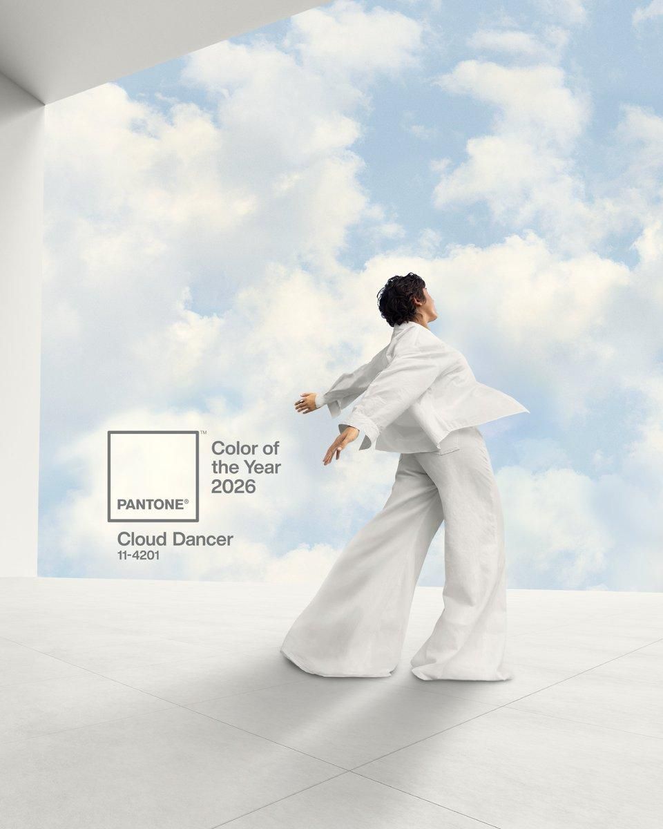 Person in white suit dancing under a cloudy sky, Pantone's 2025 Color of the Year: Cloud Dancer.