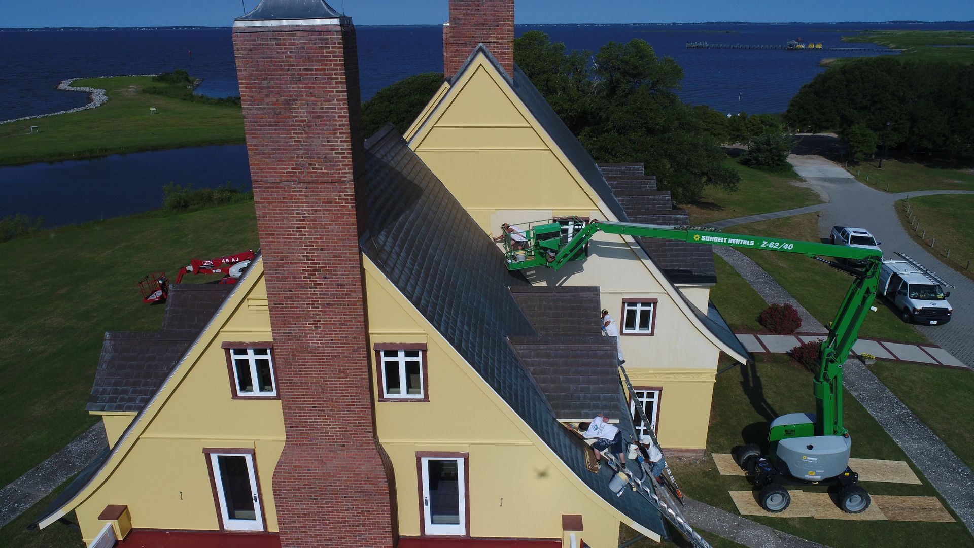 Yellow multi-story house with white trim and a blue sky.