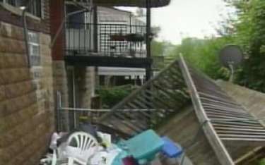 House exterior with broken fence and debris; balcony visible.