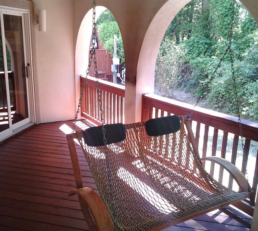 Wooden porch with a hammock swing, overlooking a wooded area.
