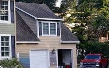 Two-story house with a garage, light-colored siding, and a red pickup truck parked outside.