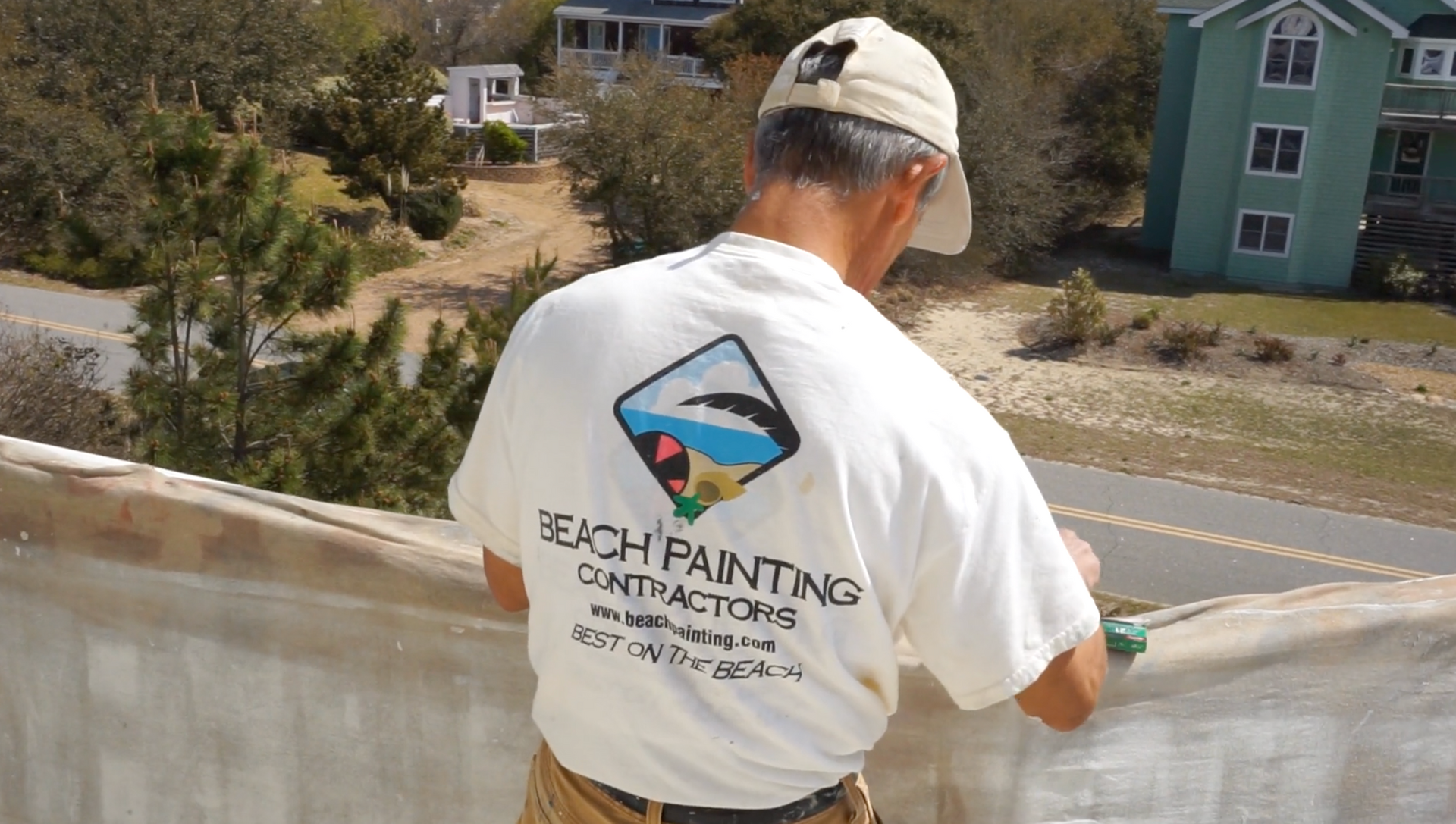 Man in cap applying sealant to a rooftop, logo on shirt says 