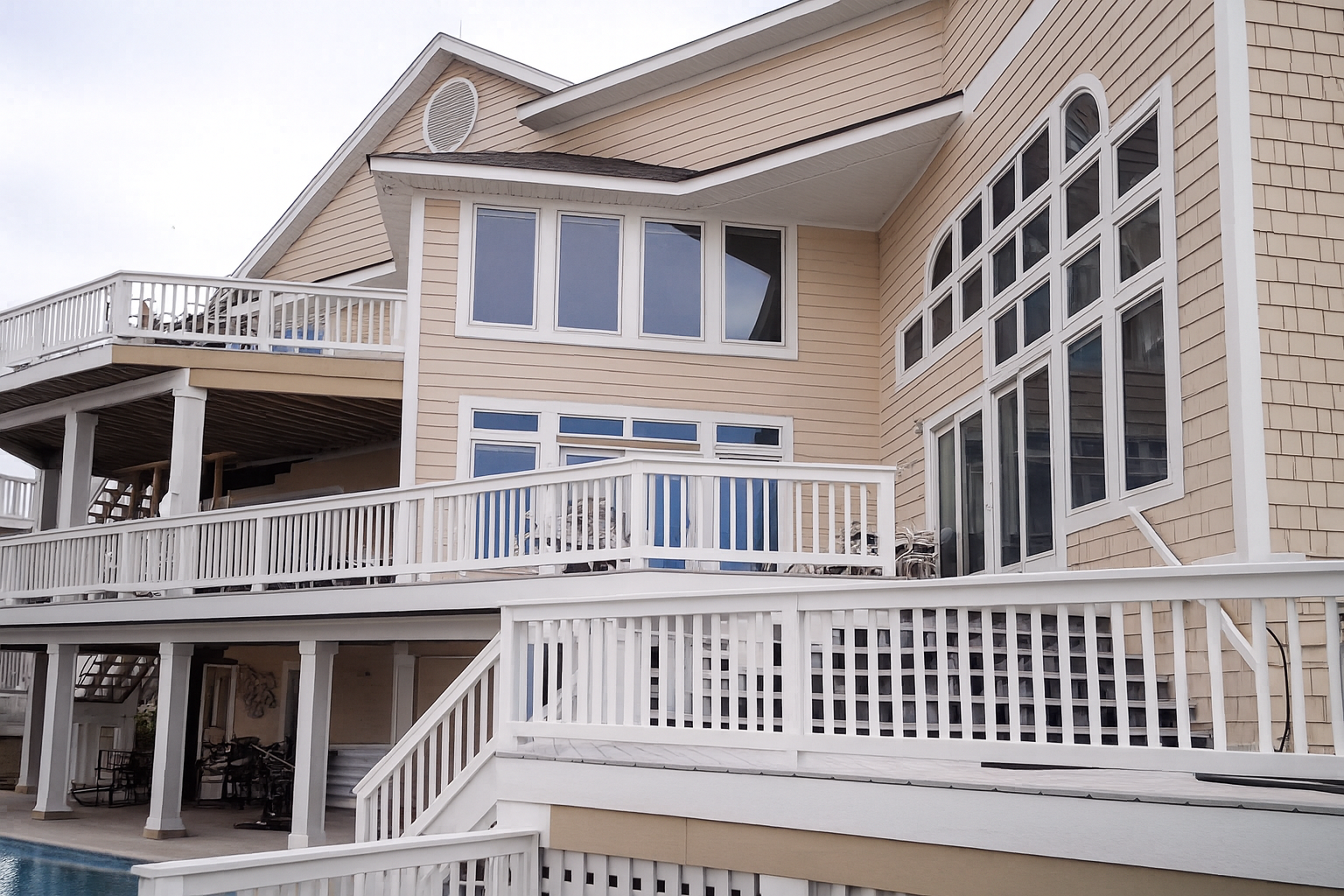 Beige house with white balconies, stairs, and tall windows.