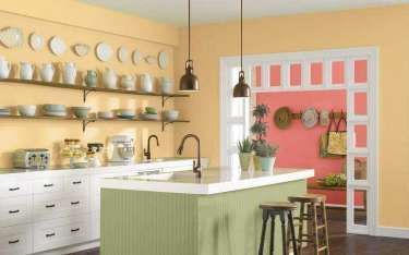 Kitchen with pale yellow walls, green island, white cabinets, and plates displayed on shelves.