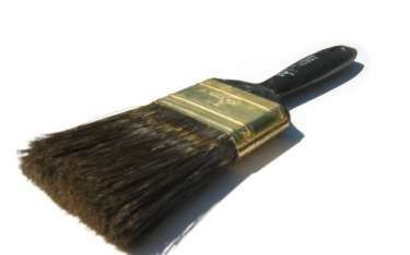 Paintbrush with dark bristles and a black handle, lying on a white surface.
