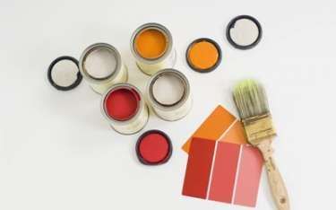 Open paint cans with red and orange paint, color swatches, and a paintbrush on a white surface.