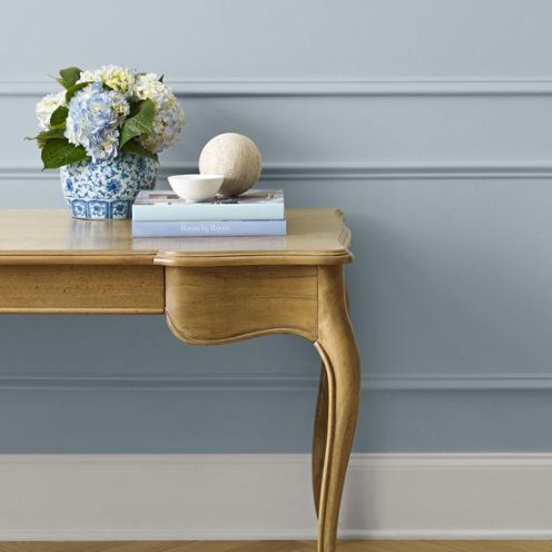 Gold table with flowers and books against a blue wall with trim.