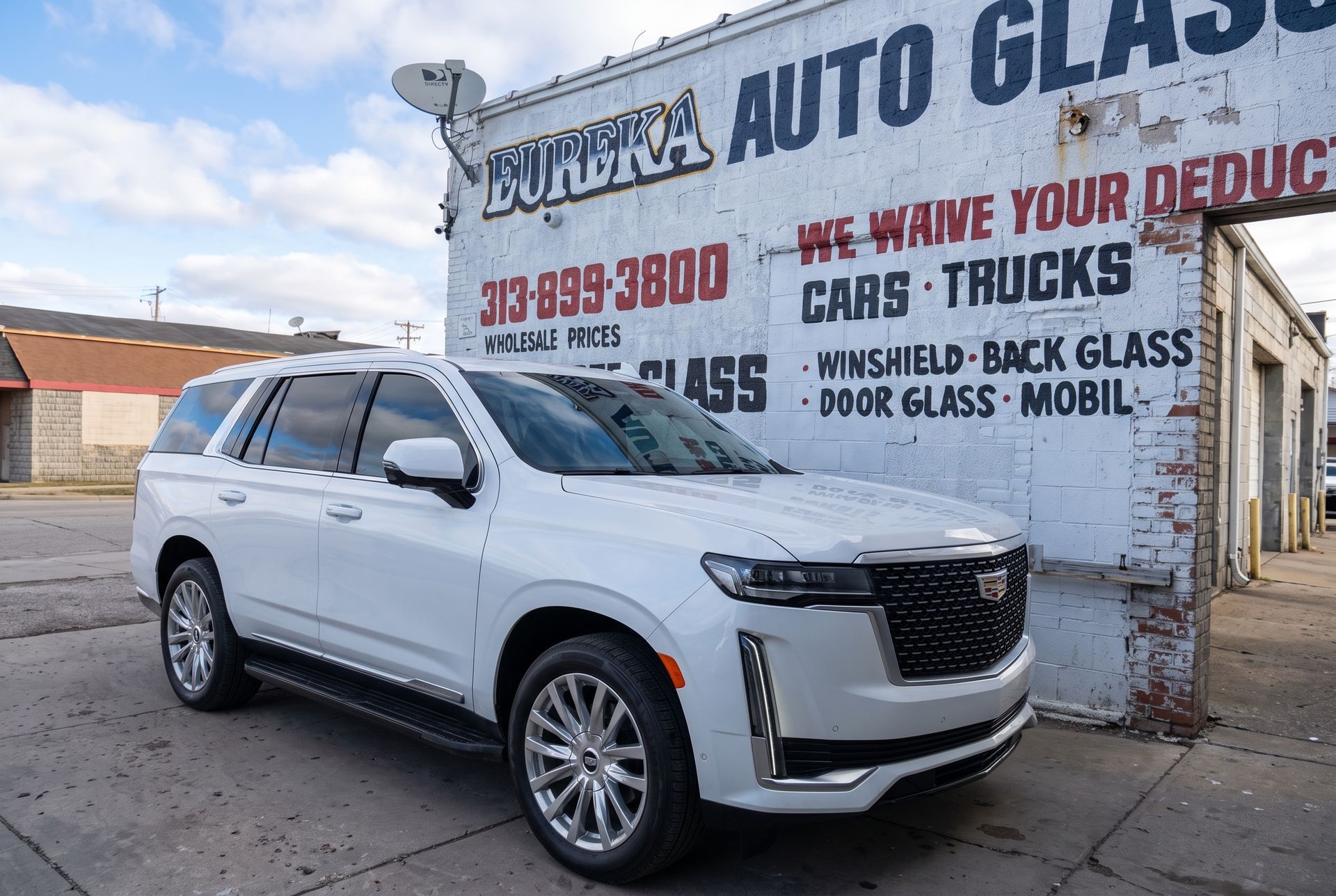White SUV parked outside an auto glass shop with faded painted signage on the wall