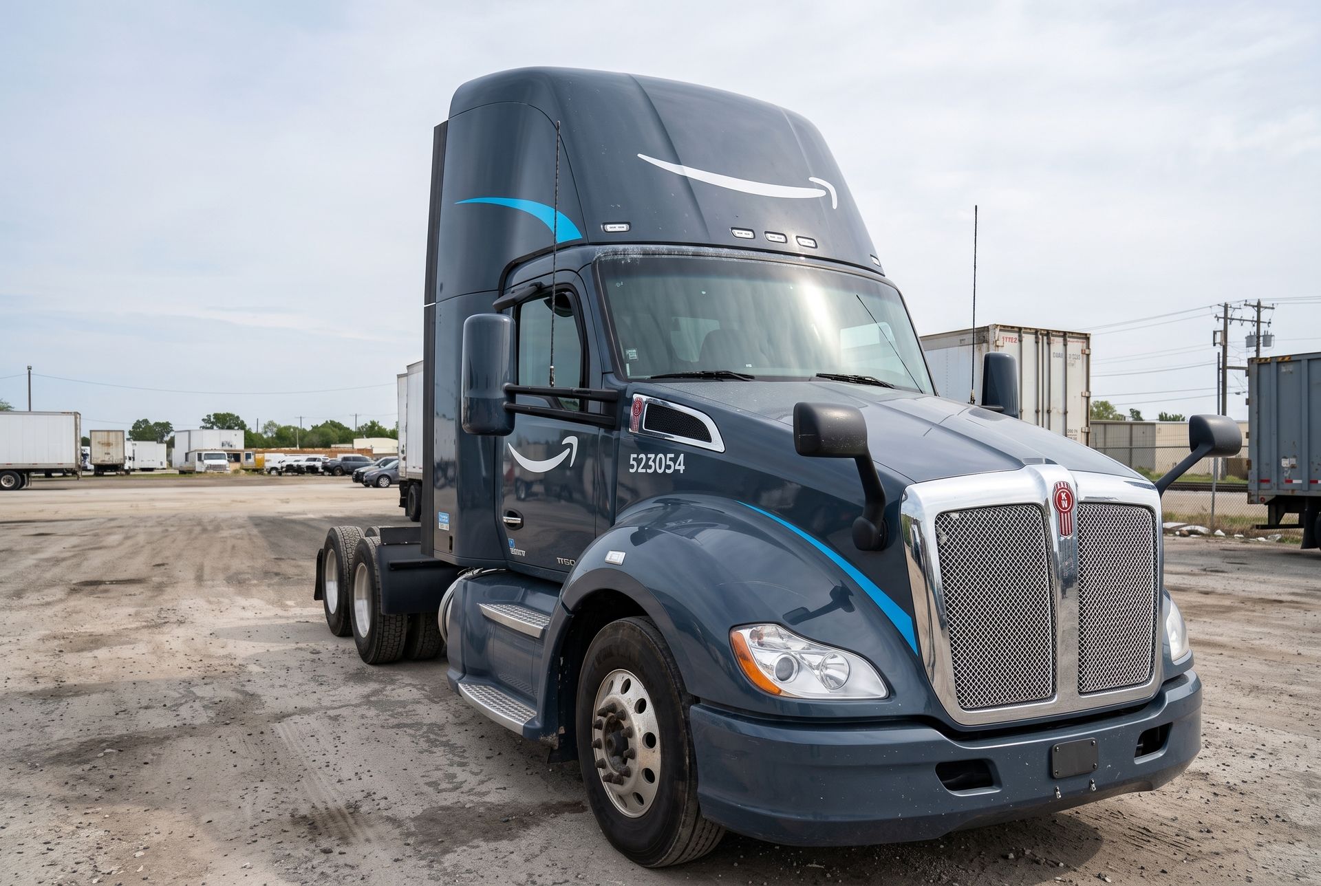 Blue semi-truck parked on a gravel lot under a cloudy sky