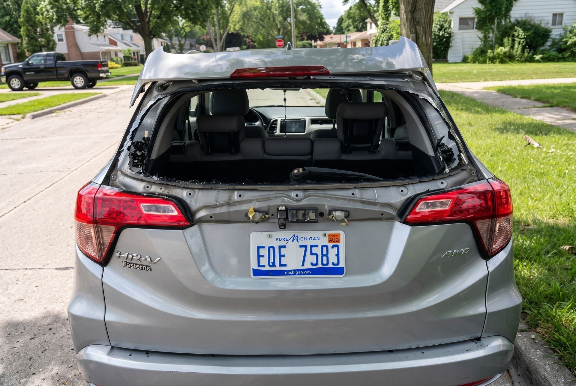 White SUV parked in a suburban driveway, rear three-quarter view with houses in the background