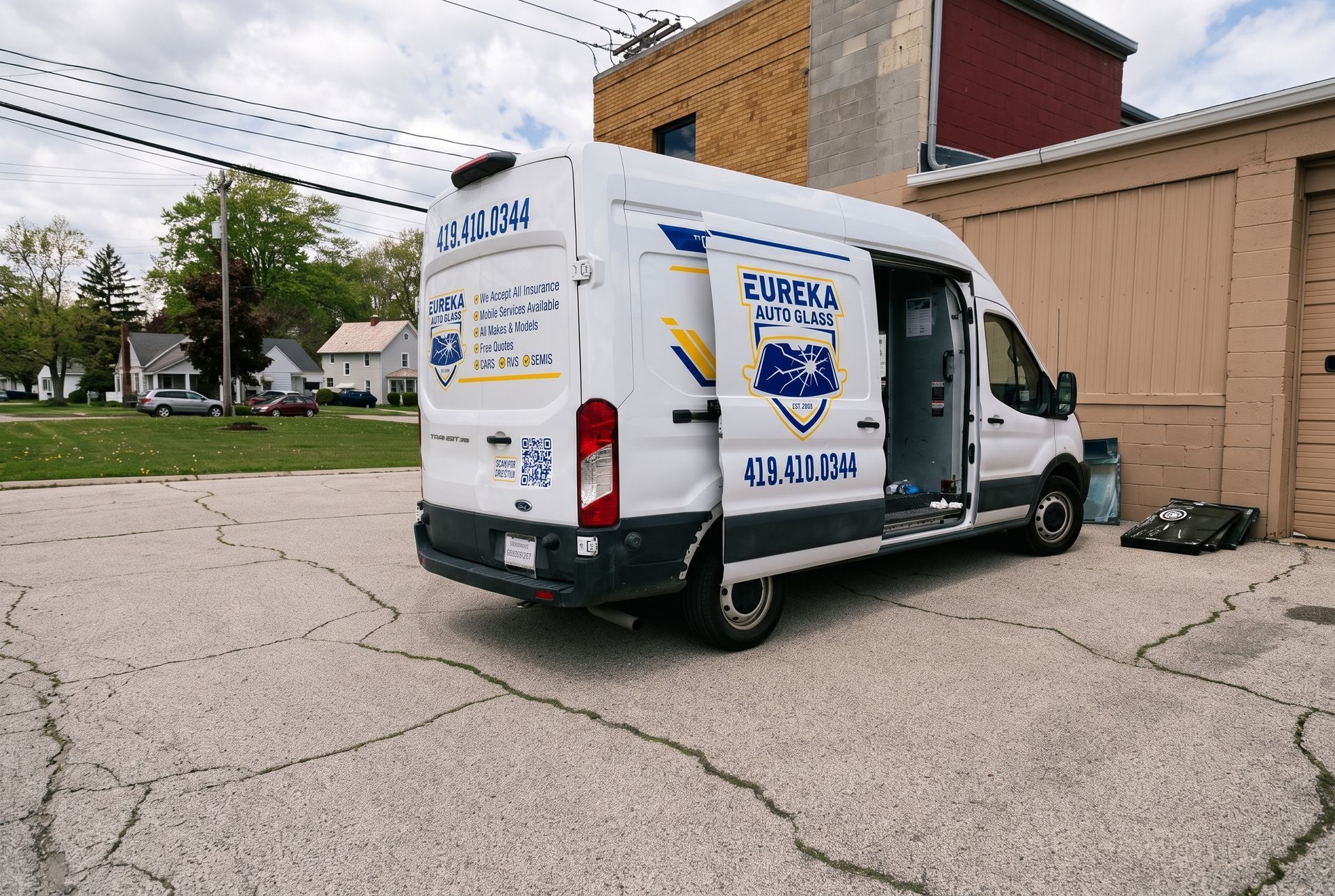White delivery van parked by a brick building, with large blue graphics on the back door.