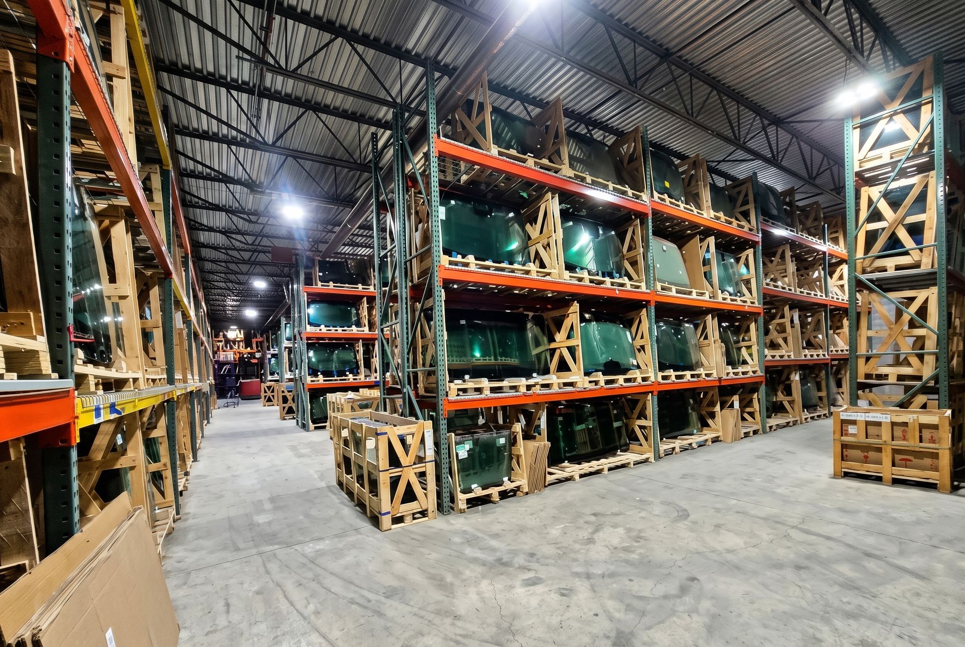 Interior of a large warehouse with tall metal shelving, wooden crates, and a concrete floor