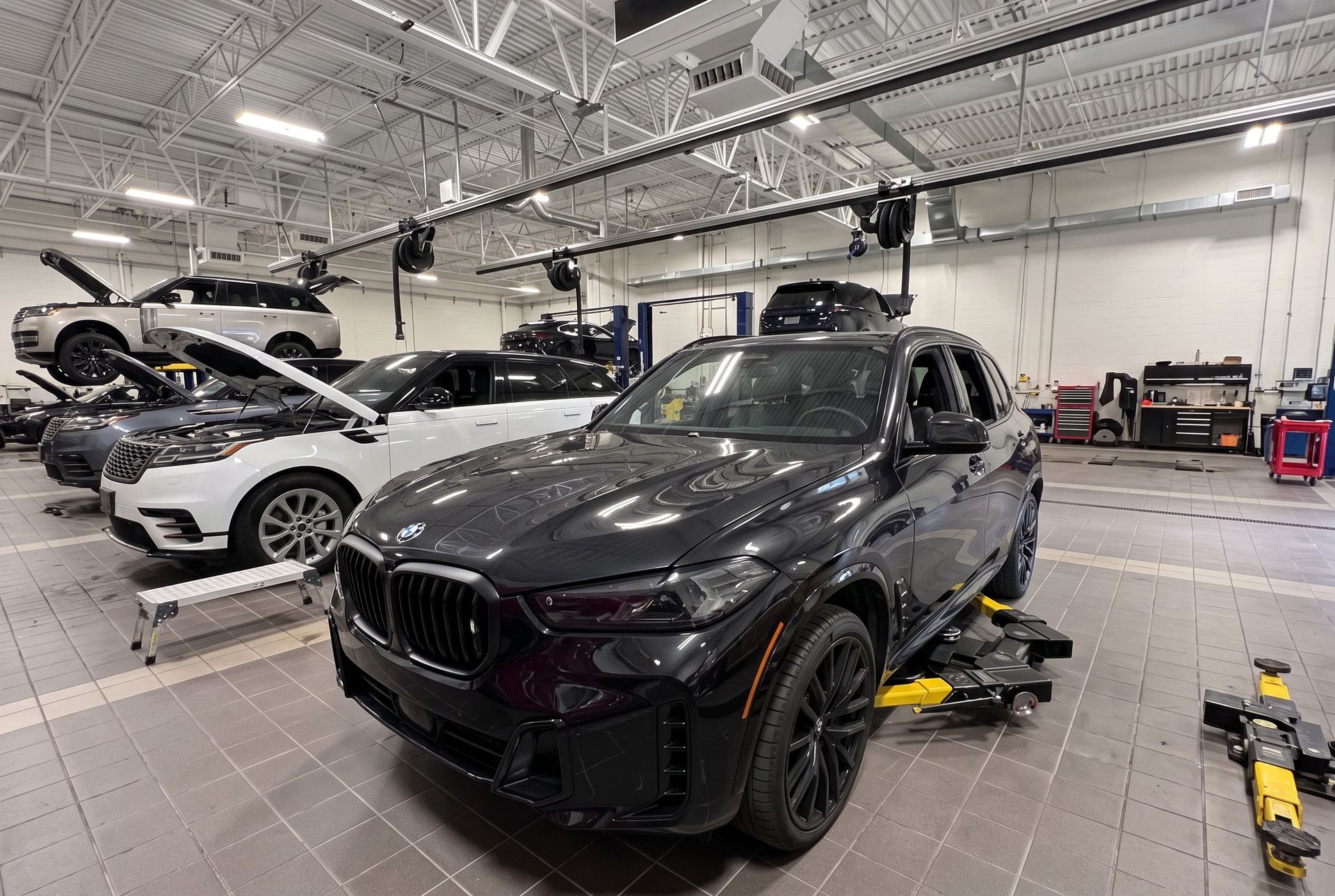 Black SUV in a bright auto shop, surrounded by tools and other cars during maintenance
