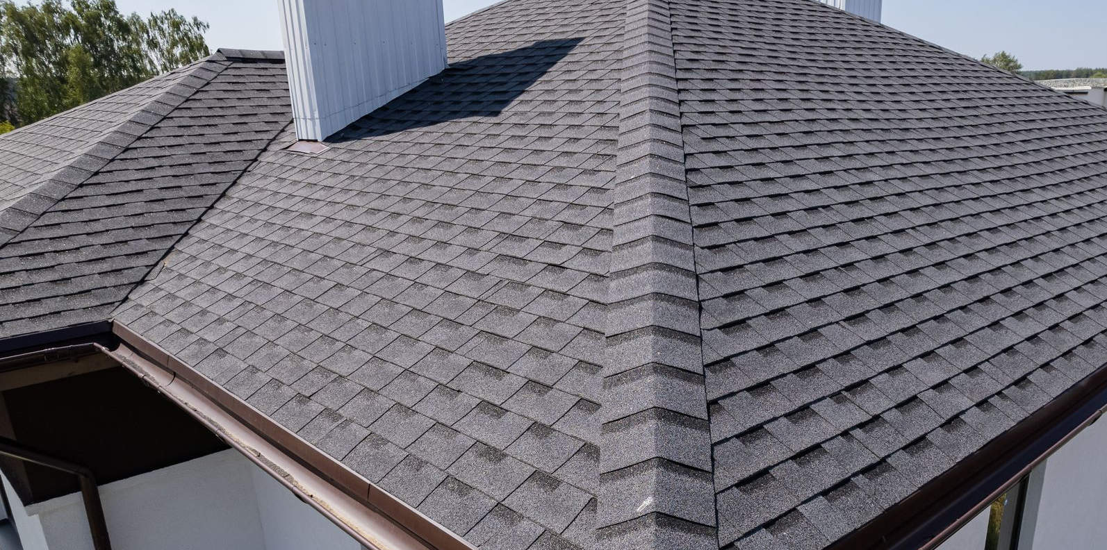 Gray shingled roof with dormer and white chimney on a house