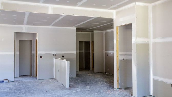 Unfinished interior room with drywall, exposed doorways, and construction debris on the floor.