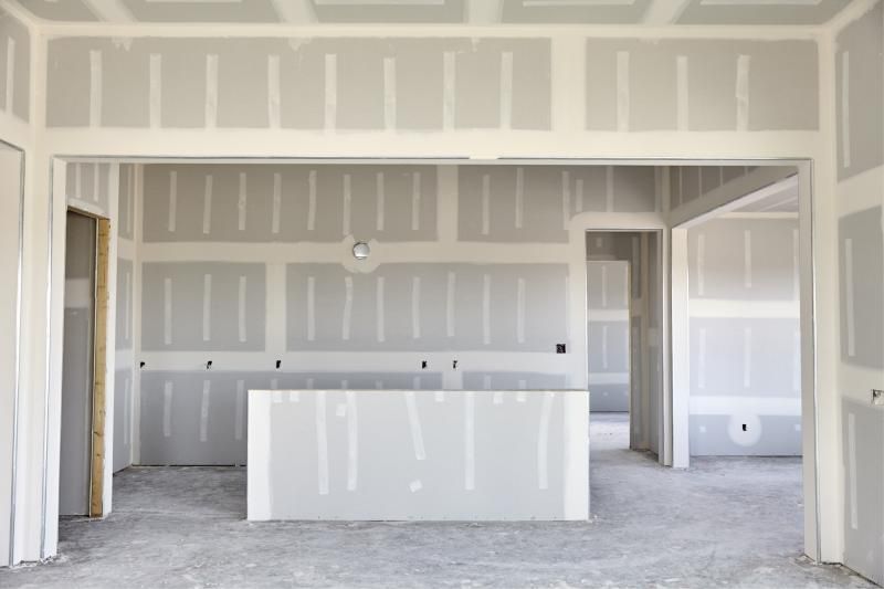 Unfinished kitchen with white drywall, a central island, and open doorways to adjacent rooms.