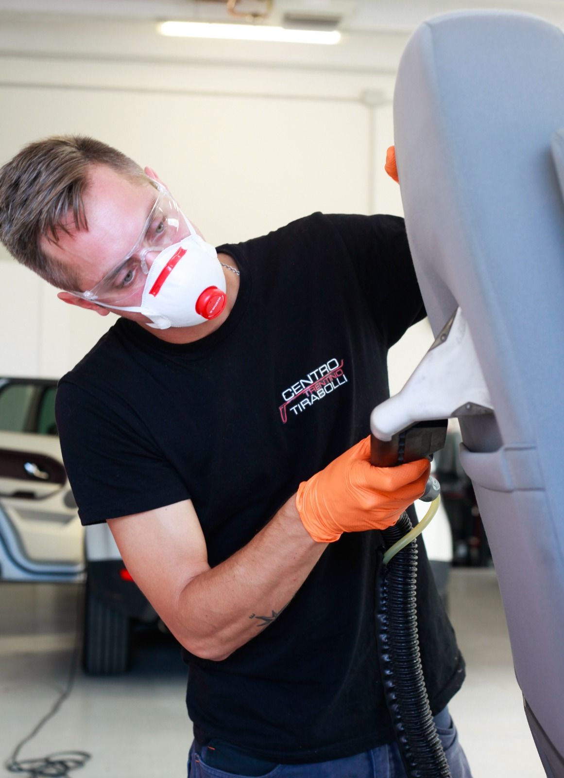 Un uomo che indossa una maschera e guanti sta lavorando su un sedile di un'auto