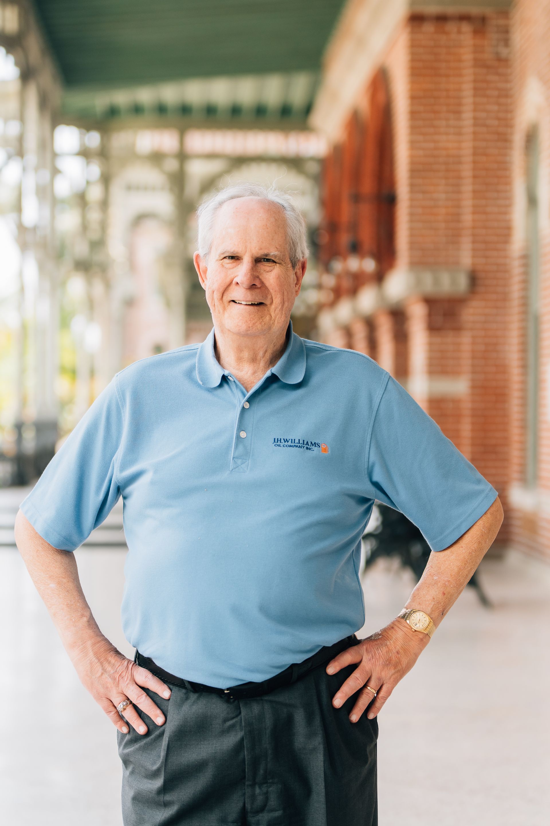 A man in a blue shirt is standing with his hands on his hips.