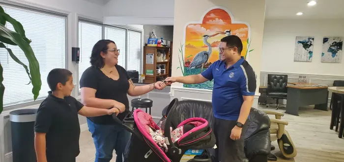 Two people shake hands inside the shop, with a child standing nearby. | AMO Auto Care