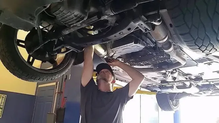 Mechanic working under a lifted car in an auto repair shop | AMO Auto Care