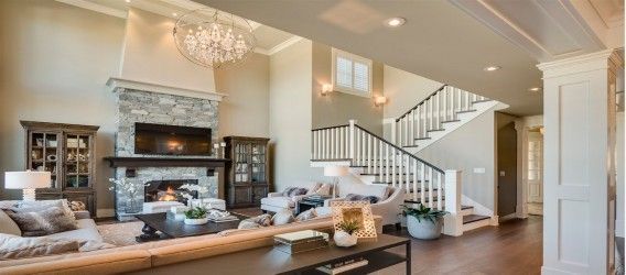 Bright living room with fireplace, chandelier, sofas, and staircase in a modern home