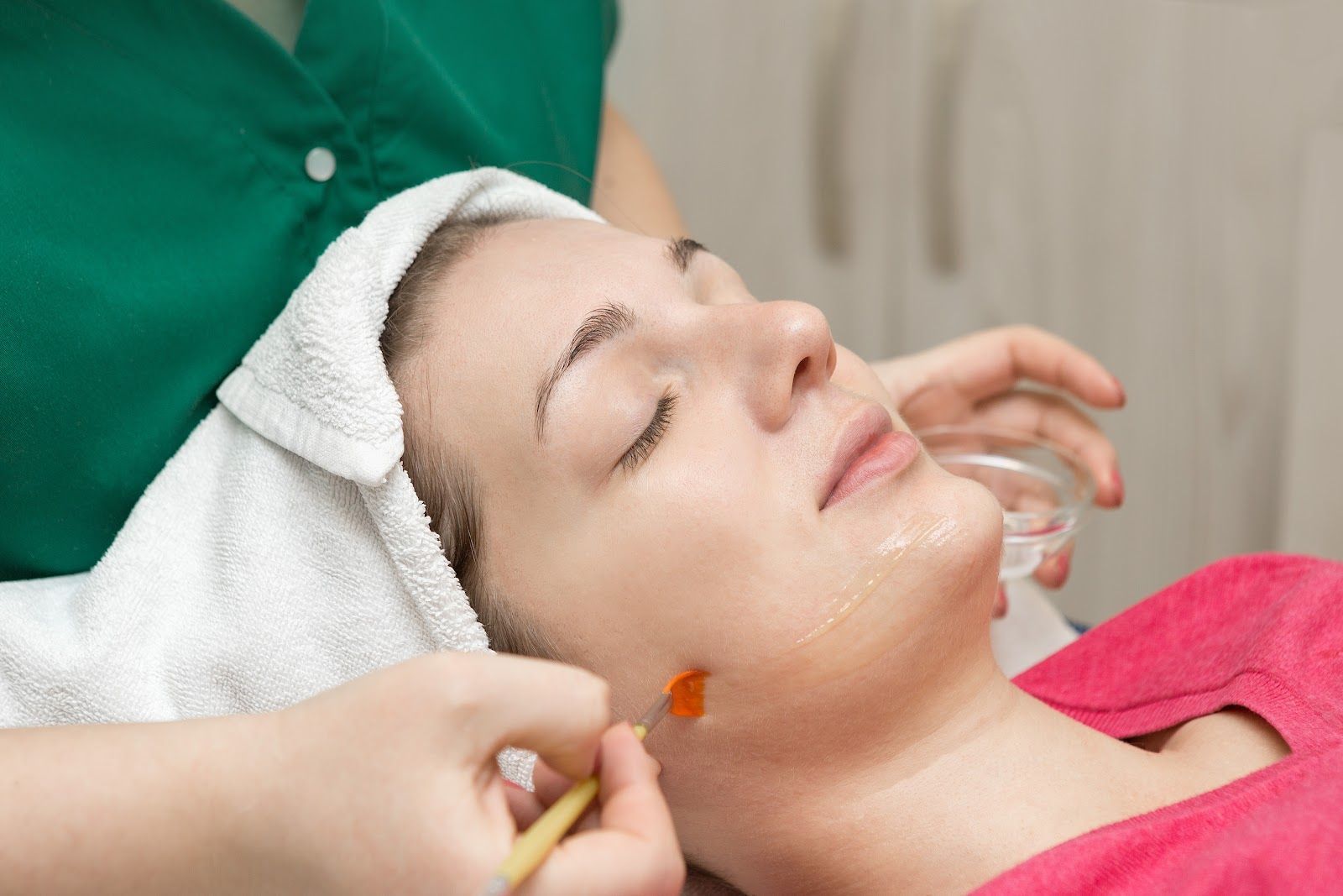 Woman receiving a facial treatment with cream applied to her cheek in a spa setting