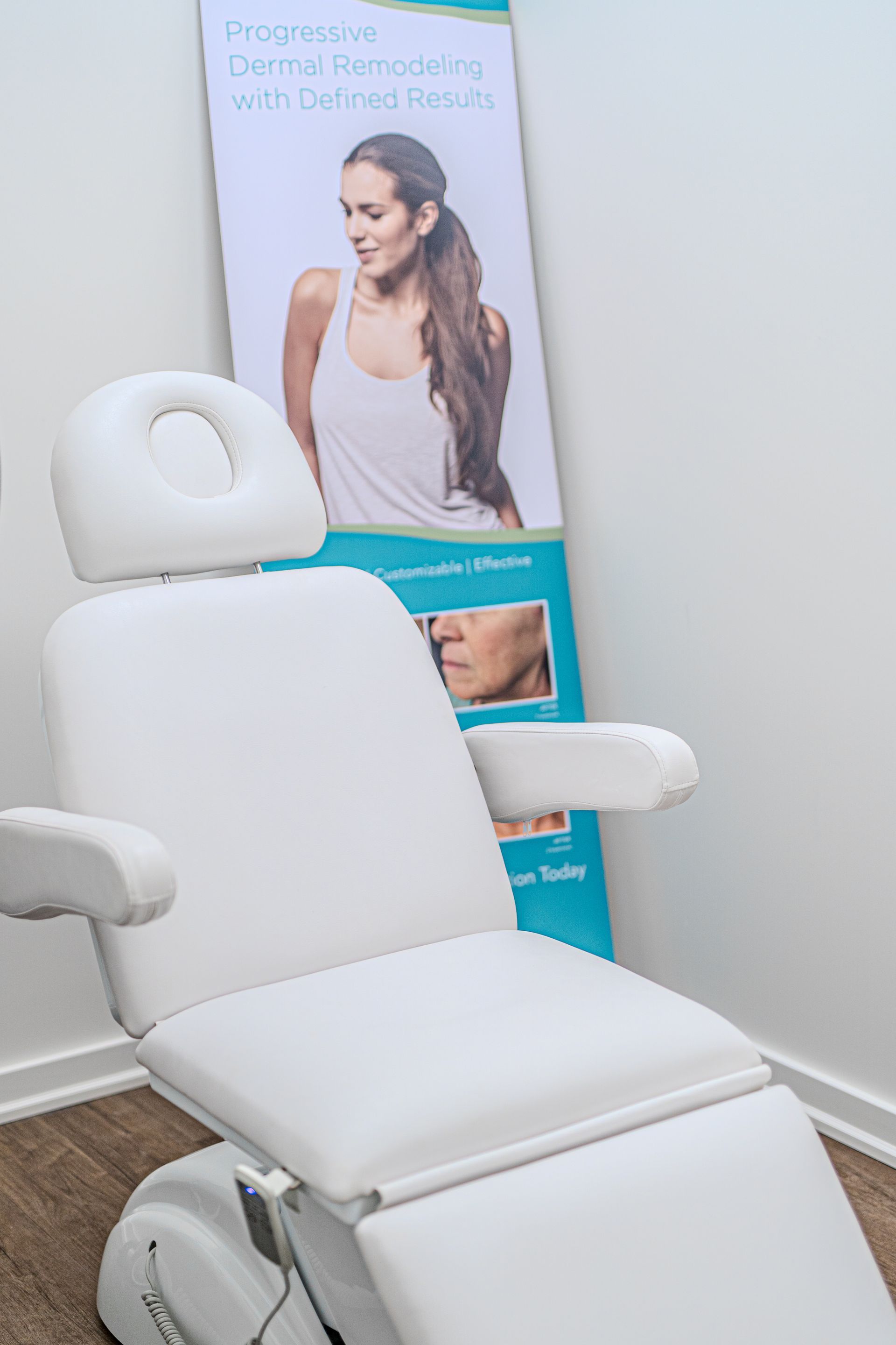 A white chair is sitting in a room next to a poster of a woman.