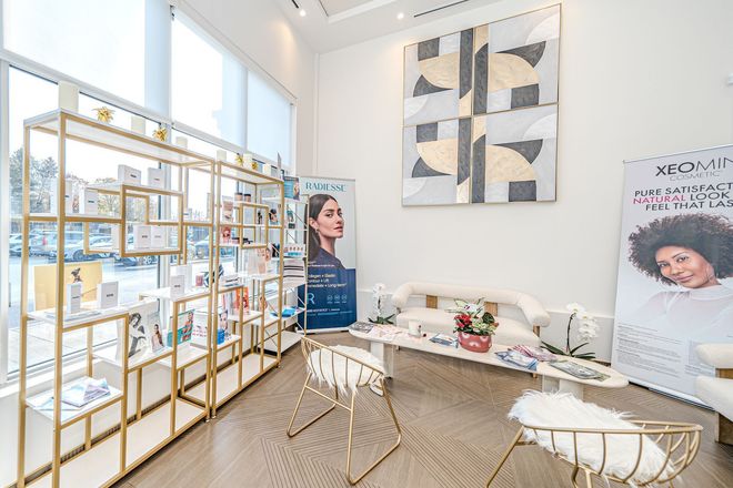 Bright boutique showroom with gold shelves, white decor, abstract wall art, and a woman standing by the display.