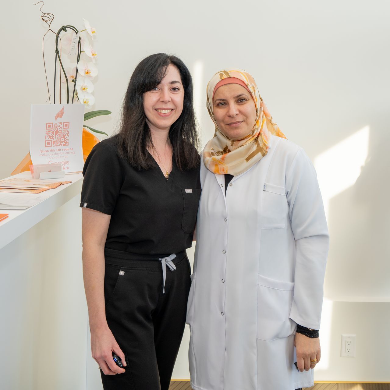 Two women in scrubs are posing for a picture in a room.